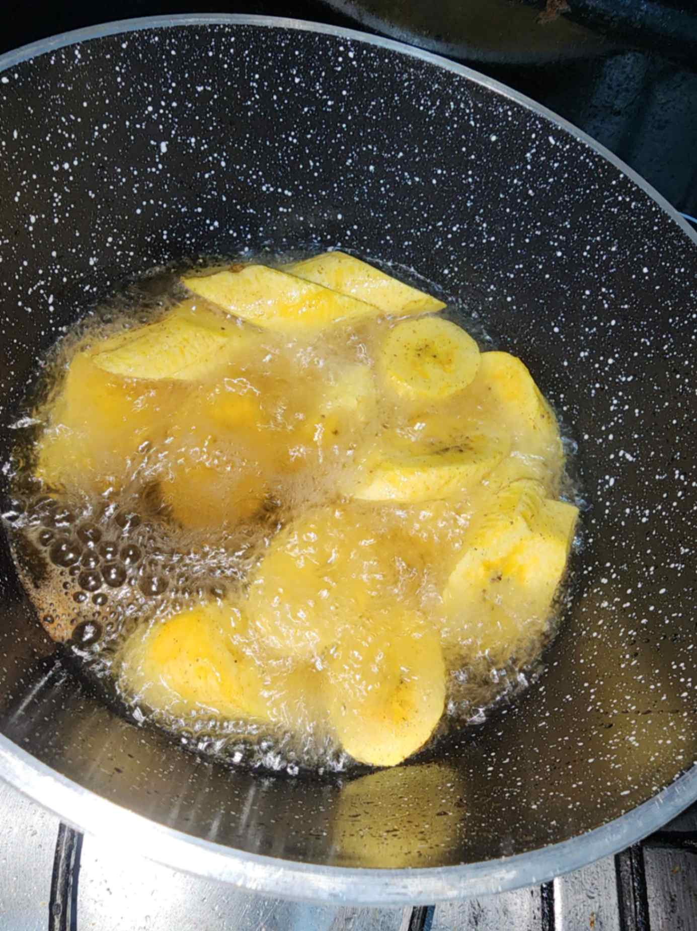Rodajas de plátano verde friéndose en aceite caliente