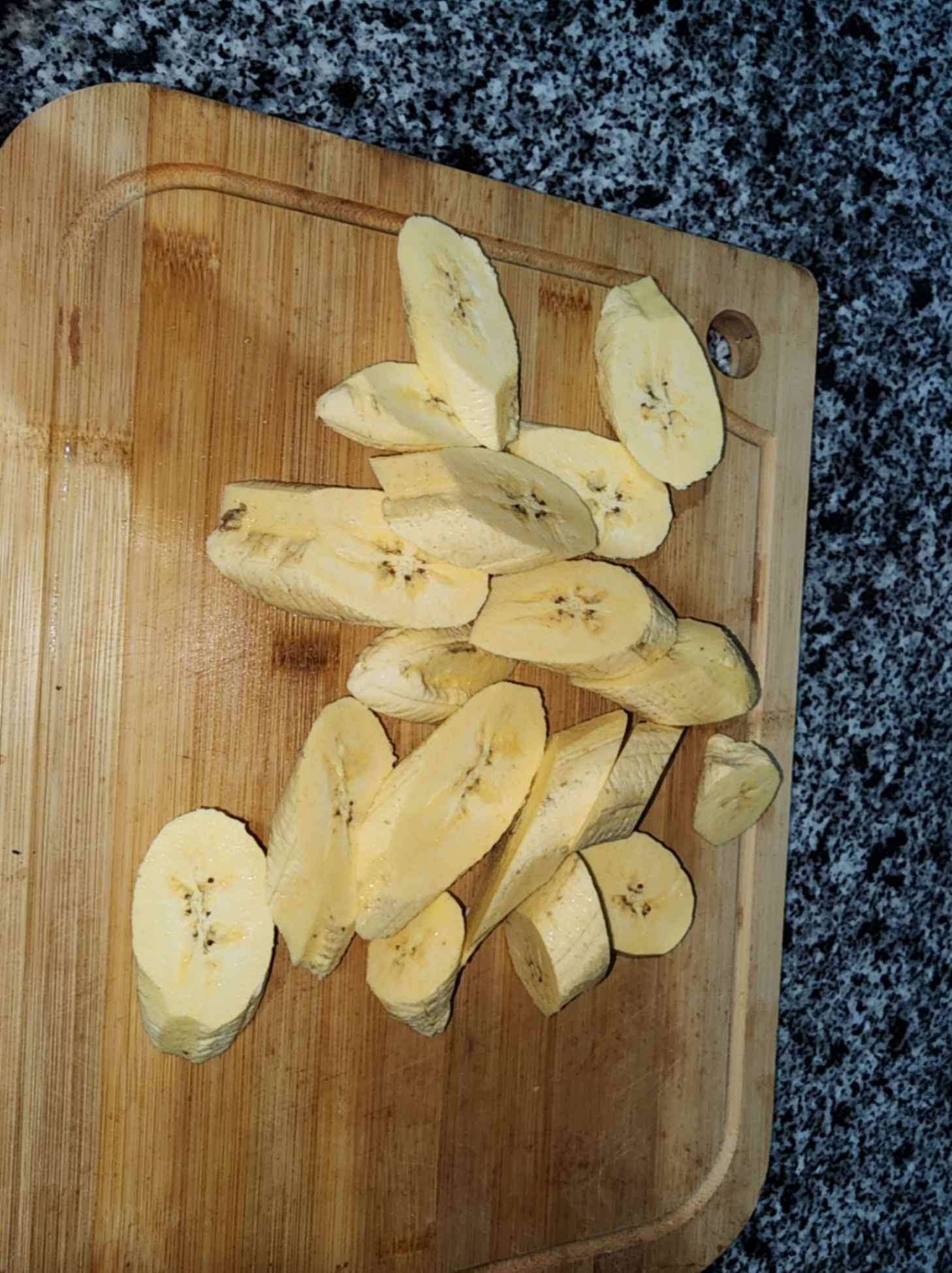 Plátanos verdes cortados en rodajas sobre una tabla de picar